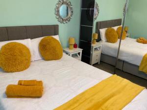 une chambre avec deux lits avec des oreillers jaunes et un miroir dans l'établissement The Sanctuary, à Corby