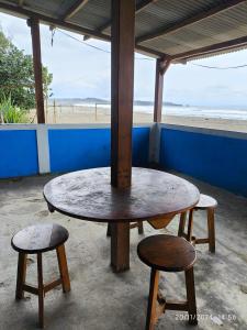 a table and two stools in front of the beach at VILLA BIRU PANTAI GOA LANGIR Sawarna in Sawarna