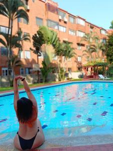 una donna in bikini seduta accanto a una piscina di Apartamento Sur De Cali Santa Anita Excelente Ubicación a Cali