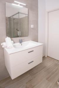 a white bathroom with a sink and a mirror at Casa Petra in Vejer de la Frontera