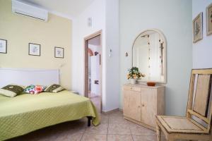 a bedroom with a bed and a mirror and a chair at Casa Murru & Sale in Irgoli