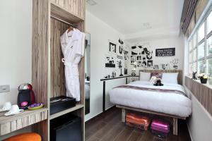 ein Schlafzimmer mit einem Bett und einem Anzug an der Wand in der Unterkunft Hotel Clover The Arts in Singapur