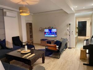 a living room with a couch and chairs and a tv at Les Nuits de Miel - Marrakech in Marrakech