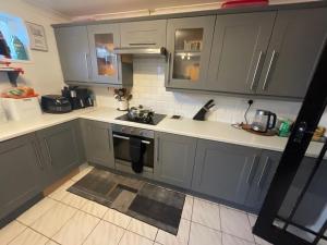 La cuisine est équipée de placards gris et d'un four avec plaques de cuisson. dans l'établissement The Sanctuary, à Corby 13 autres photos