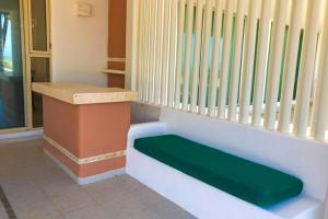 a bench with a green seat in a room at Kastelorizo Private Beachfront house in Chicxulub +38 photos