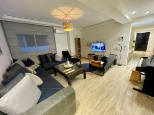 a living room with a couch and chairs and a tv at Les Nuits de Miel - Marrakech in Marrakech