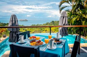 a table with food and drinks next to a pool at Villa Roca Boutique Resort & Suites - ADULT ONLY in Manuel Antonio