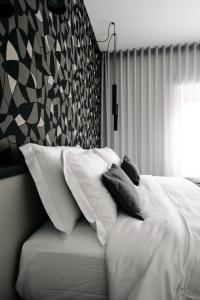 una camera da letto con un letto con lenzuola e cuscini bianchi di B&B LUMAS a Roma