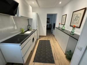 a white kitchen with a sink and a dishwasher at Retiro verde en Madrid in Quintana