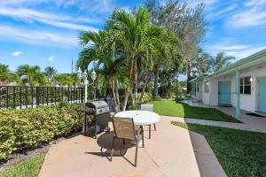 d'une terrasse avec une table, un grill et des palmiers. dans l'établissement Cozy Studio - Pool in Lake Worth, à Lantana