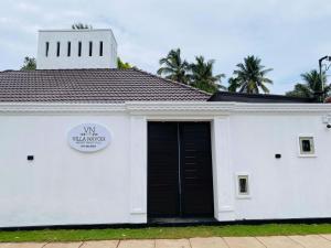 a white building with a black door and palm trees at Villa Navodi in Negombo