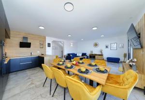 een eetkamer en een woonkamer met een tafel en gele stoelen bij Villa Good Vibes with heated pool in Kod Mula