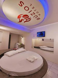 a bedroom with a large white bed with a sign on the ceiling at Búzios Motel in São Luís