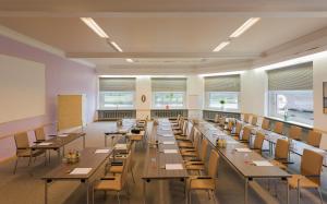 フランクフルト・アム・マインにあるTagungshotel Höchster Hofのテーブルと椅子と窓のある広い部屋