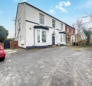 Una casa blanca con un coche aparcado delante. en Zetland House Apartment - First floor with garden and parking, en Southport