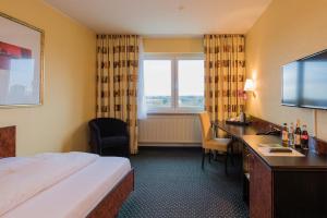 フランクフルト・アム・マインにあるTagungshotel Höchster Hofのベッドと机とテレビがあるホテルの部屋