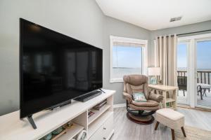 a living room with a large television and a chair at Beachside 323 Waterfront Condo in Traverse City