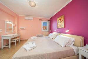 a bedroom with two beds and a pink wall at Stella Hotel Apartments in Fiskardo