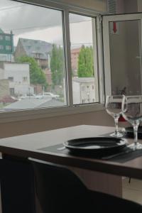 Una mesa con dos vasos y un plato y una ventana. en Gente del Sur - Yehuin, en Ushuaia