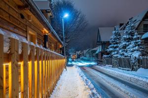 eine schneebedeckte Straße mit einem Zaun und Bäumen in der Unterkunft Willa Zofiówka in Zakopane + 124 Fotos