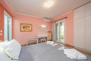 a bedroom with pink walls and a bed and a desk at Stella Hotel Apartments in Fiskardo