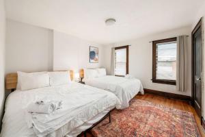 a white bedroom with two beds and a rug at The Cobblestone Townhouse - 2 BR -German Village in Columbus