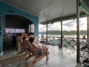 two people sitting in chairs looking out at the water at Casa Los Delfines in Tortuguero