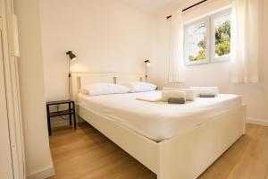 a large white bed in a room with a window at Apartments Kržanić in Podgora