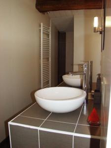 Un baño con un gran lavabo blanco sobre un mostrador. en Chambres d'Hôtes Les laitières, en Beaurepaire