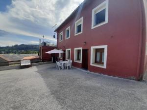 a red building with a table and chairs in front of it at Apartamentos Miravalles B in Villaviciosa