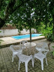 a table and chairs under a tree next to a pool at Casa com piscina proximo da praia in Itapoa