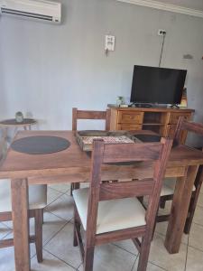 a wooden table with chairs and a television on a desk at LUMINOSO Y COMPLETO DEPARTAMENTO CENTRO Villa Carlos Paz in Villa Carlos Paz