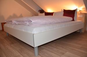 a bed with white sheets and red pillows on it at Apartment U Karla in Třeboň
