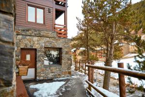 a stone house with a wooden door in the snow at Con Parking y Escritorio I Apartamento en Incles I AndBnB in Canillo