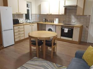 a kitchen with a wooden table and a table and chairs at SAV Stays Apartments Watford in Watford