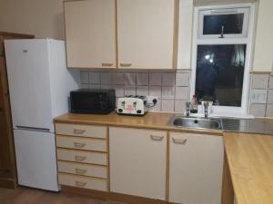 a kitchen with a white refrigerator and a sink at SAV Stays Apartments Watford in Watford