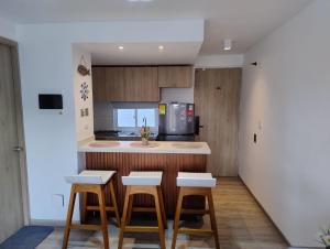 a kitchen with three stools and a counter top at Apartamento Turístico Santa Marta punta gaira in Santa Marta