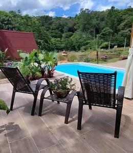 due sedie e un tavolo di fronte alla piscina di Sitio Lar da Terra a São Roque