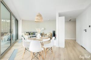 a dining room with a table and white chairs at Pinea 110 - basen, sauna, jacuzzi w cenie pobytu - bezpośredni widok na morze - Easy - Rent Apartments in Pobierowo