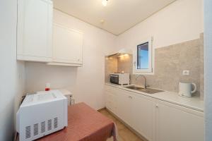a kitchen with white cabinets and a sink and a microwave at Stella Hotel Apartments in Fiskardo