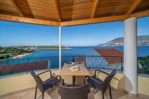a table and chairs on a balcony with a view of the ocean at Stella Hotel Apartments in Fiskardo