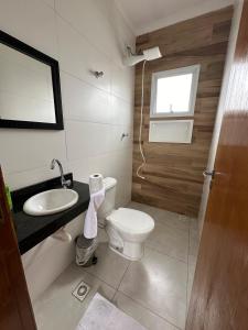 ein Badezimmer mit Toilette und Waschbecken und einem Fenster in der Unterkunft 5 Casa - Praia Guilhermina in Praia Grande