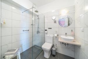a white bathroom with a toilet and a sink at Stella Hotel Apartments in Fiskardo