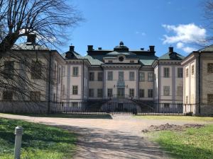 a large building with a fence in front of it at Salsta slotts paviljong in Vattholma