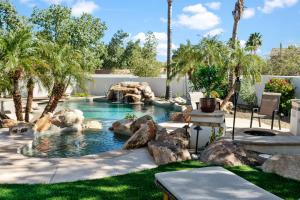 a pool with a waterfall in a backyard with palm trees at NEW Gold Dust Private Villa in Scottsdale