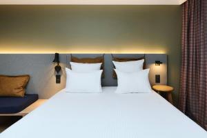 a bedroom with a large bed with white pillows at Moxy Annecy in Annecy
