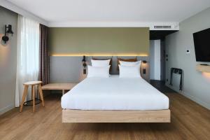 a bedroom with a large white bed and a table at Moxy Annecy in Annecy