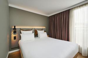 a bedroom with a large white bed and a window at Moxy Annecy in Annecy