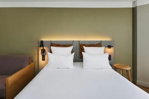 a bed with white sheets and pillows at Moxy Annecy in Annecy