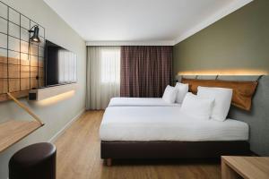 a hotel room with two beds and a television at Moxy Annecy in Annecy